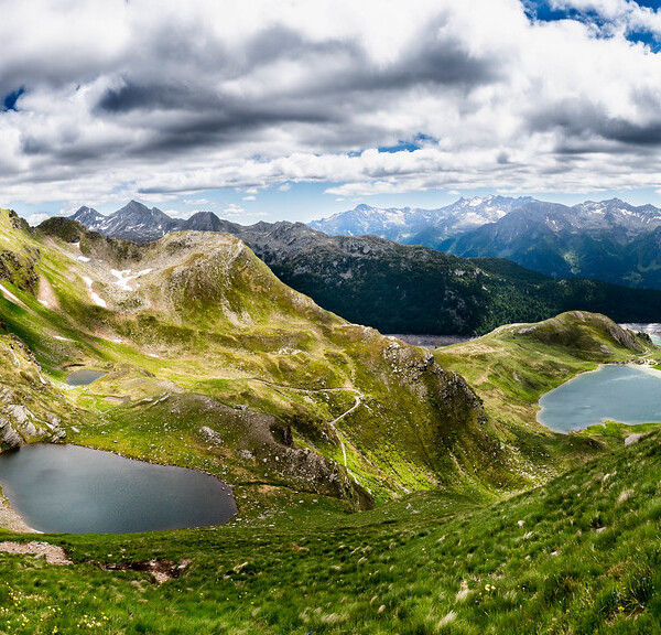 Lago di Tom: Panorama mit Bergseen, grünen Hängen und Wolken.