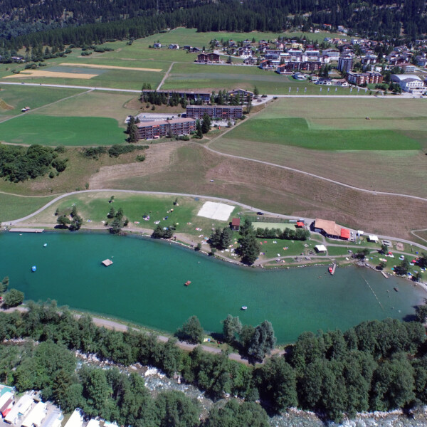 Lai Barnagn Seeansicht mit grüner Landschaft und Gebäuden im Hintergrund.