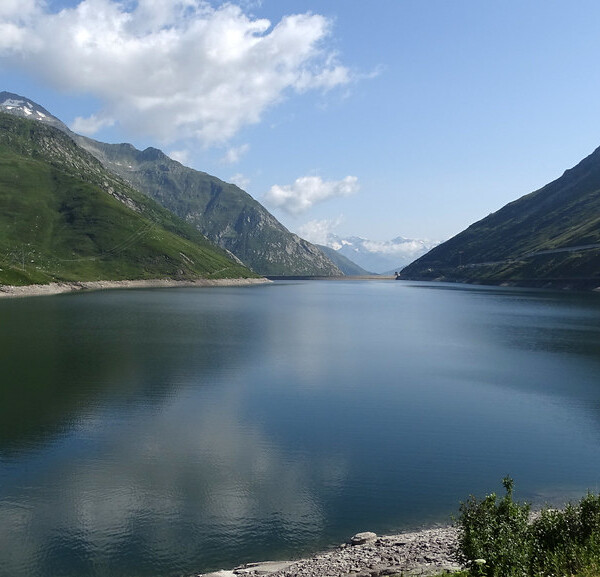 Lai da Sontga Maria: Ruhiger Bergsee mit grünen Hängen und blauem Himmel.
