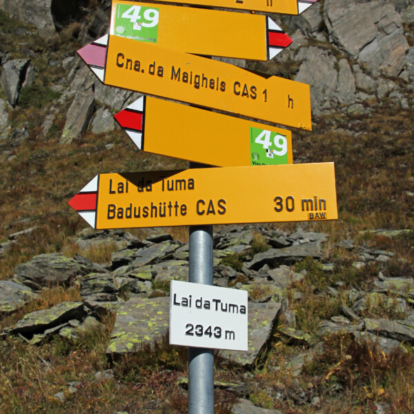 Wegweiser am Lai da Tuma (Tomasee) mit Zielen wie Oberalppass und Badushütte.