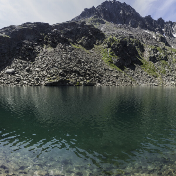 Lai da Tuma (Tomasee) Panorama mit Bergkulisse und klarem Wasser.