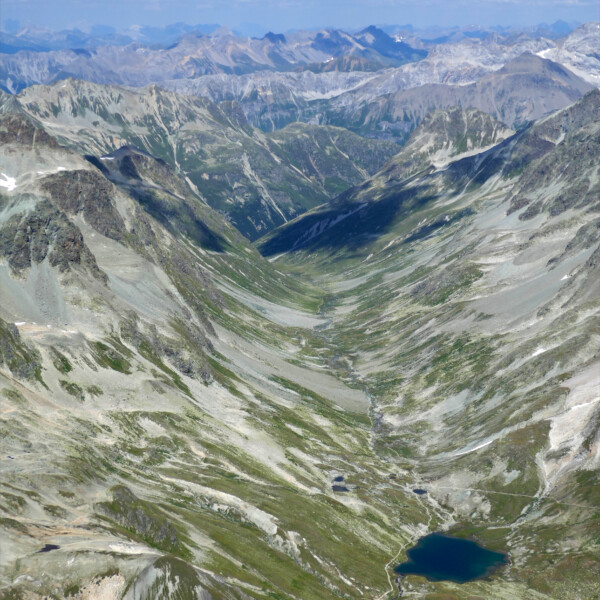 Lej Suvretta: Bergsee in den Alpen mit grünen Hängen und felsigen Gipfeln.