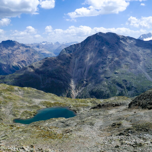 Lej dal Rosatsch: Bergsee in hochalpiner Landschaft mit Bergen und blauem Himmel.