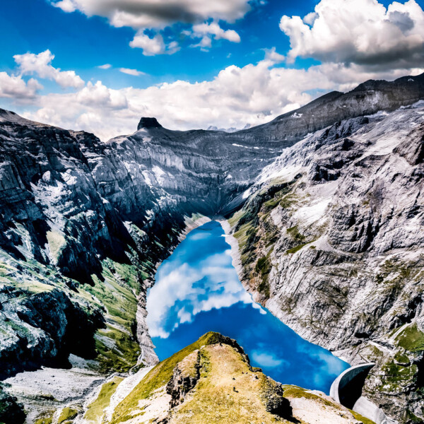 Limmerensee-Stausee in den Alpen mit blauem Wasser und Wolkenreflexionen.