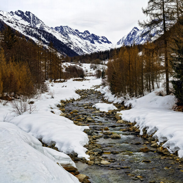 Winterliche Berglandschaft mit schneebedeckten Gipfeln und einem Fluss.