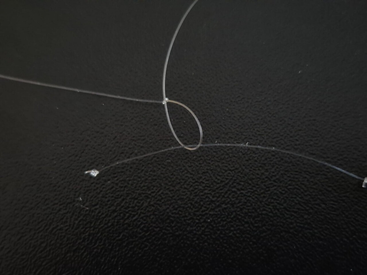 Angelschnur mit Knoten auf schwarzem Grund. Sbirolino fischen.