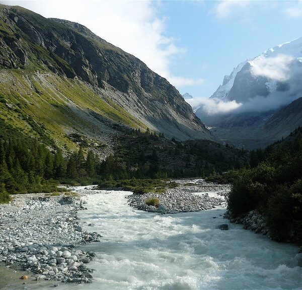 Wilder Fluss in einem Tal mit Bergen und grünen Hängen. Navisence.