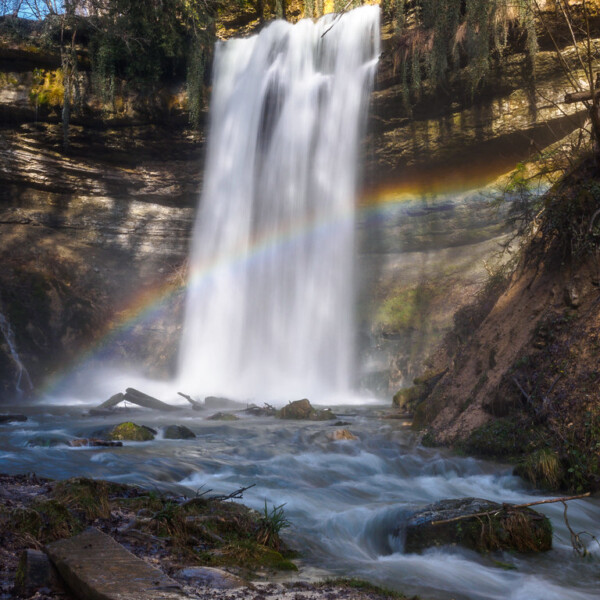 Wasserfall Nozon mit Regenbogen im Gegenlicht, malerische Naturkulisse.
