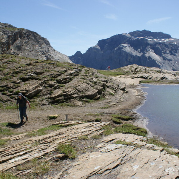 Wanderer am Plan des Roses Sees vor Bergkulisse. Sonniger Tag in den Alpen.