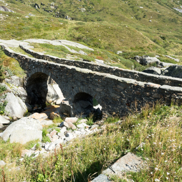 Steinbrücke über Rein da Medel in alpiner Landschaft.