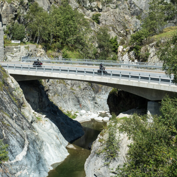 Brücke über Rein da Medel mit zwei Motorrädern vor felsiger Landschaft.