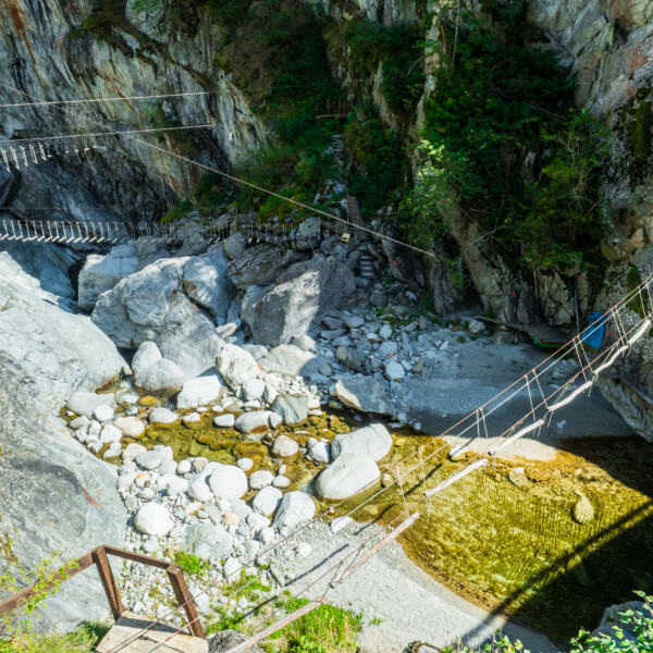 Hängebrücken über den Rein da Medel, eingebettet in felsige Landschaft.
