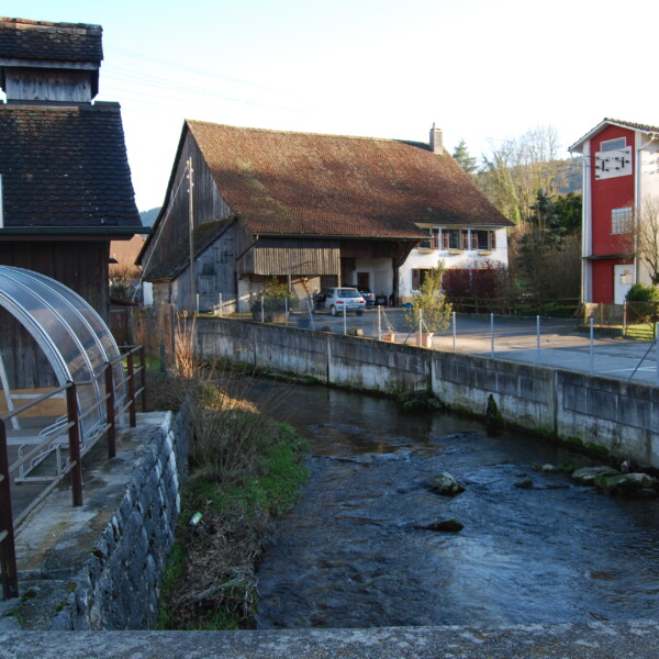 La Cure, Schweiz: Flusslauf mit Gebäuden. Scheulte.