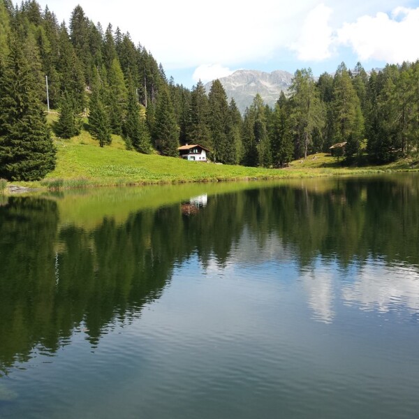 Schwarzsee (Davos Laret) mit Haus am Ufer und Spiegelung im Wasser.