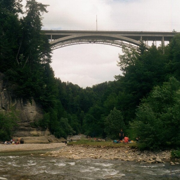 Schwarzwasser-Fluss unter einer hohen Brücke, umgeben von üppigem Grün.
