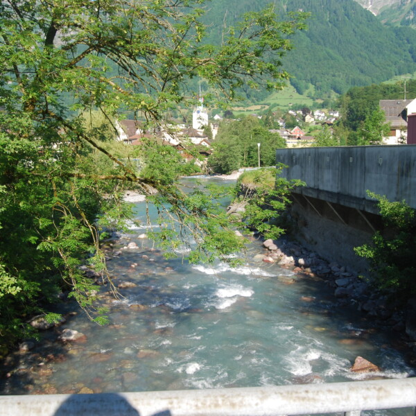 Fluss Sernf in der Schweiz mit Brücke und grüner Landschaft.