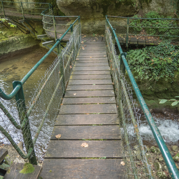 Holzbrücke über den Seyon-Fluss mit Geländer und Maschendrahtzaun