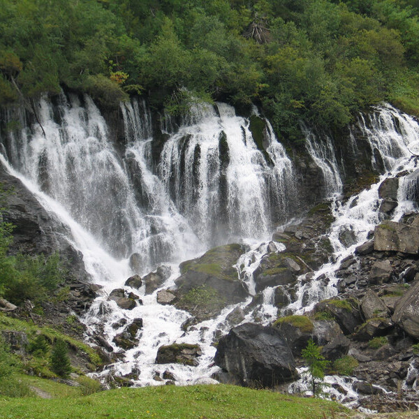 Wasserfall in Simme, Schweiz, stürzt über Felsen und grüne Vegetation.