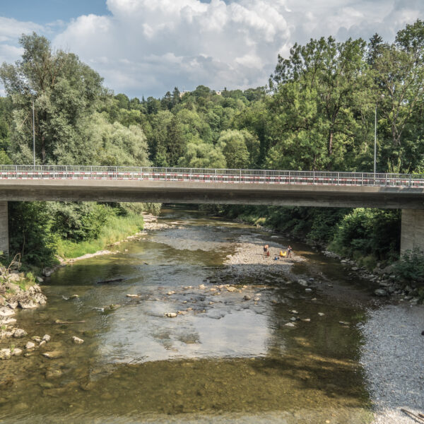 Brücke über den Sitter-Fluss mit spielenden Menschen im Wasser, umgeben von Bäumen.