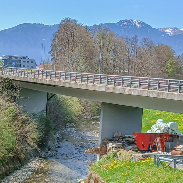 Brücke über die Steiner Aa mit Bergen im Hintergrund. Bauarbeiten am Ufer.