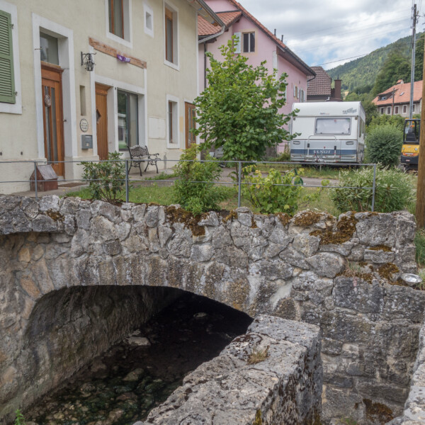 Historische Steinbrücke in Suze (Schüss) mit Wohnwagen im Hintergrund.