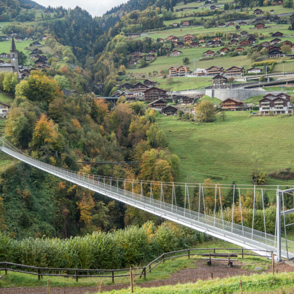 Hängebrücke in Vièze mit Blick auf ein Schweizer Dorf und grüne Hügel.