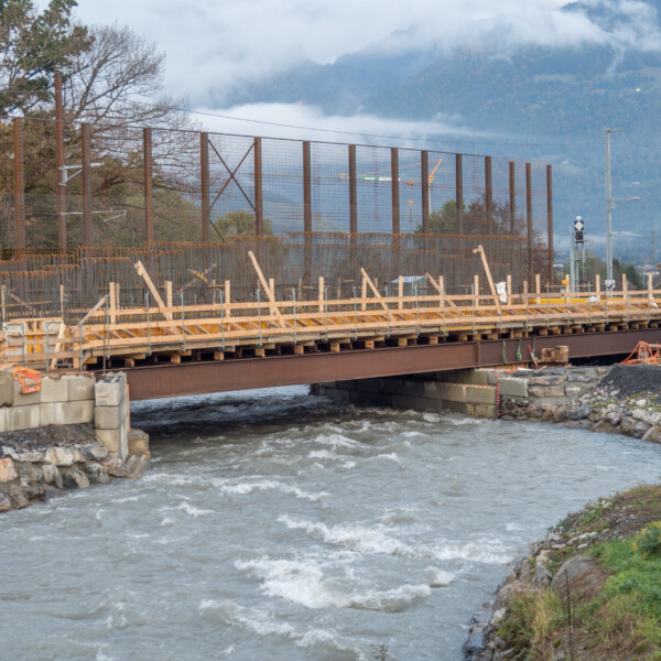 Vièze-Brücke im Bau über einen Fluss, mit Bergen im Hintergrund.