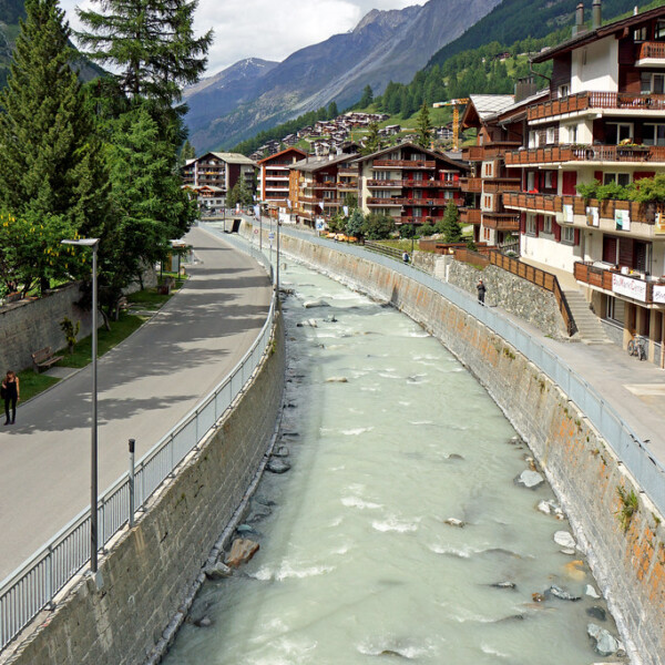 Vispa-Fluss in Zermatt mit Gebäuden und Bergen im Hintergrund.