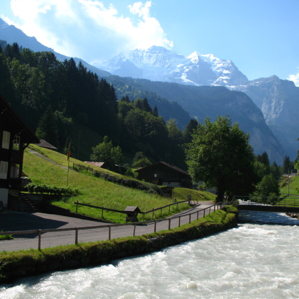 Weisse Lütschine Fluss in den Schweizer Alpen mit Häusern und Bergen im Hintergrund.