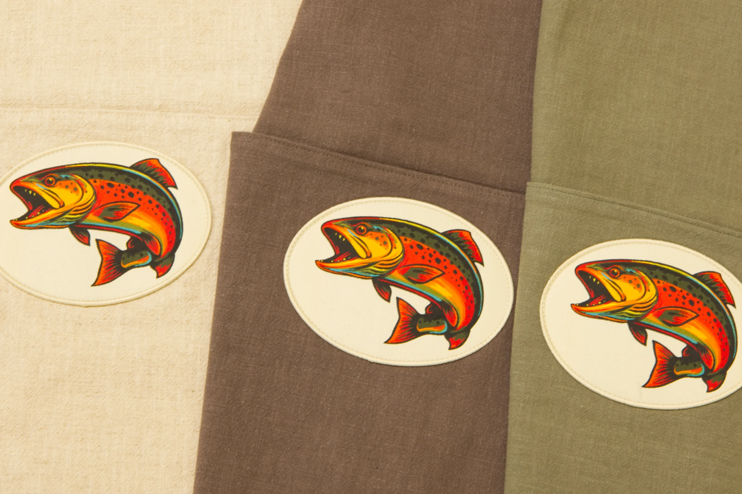 Drei Fischsäcke in Beige, Braun und Grün mit Fisch-Patch. Sicherer Fischtransport.