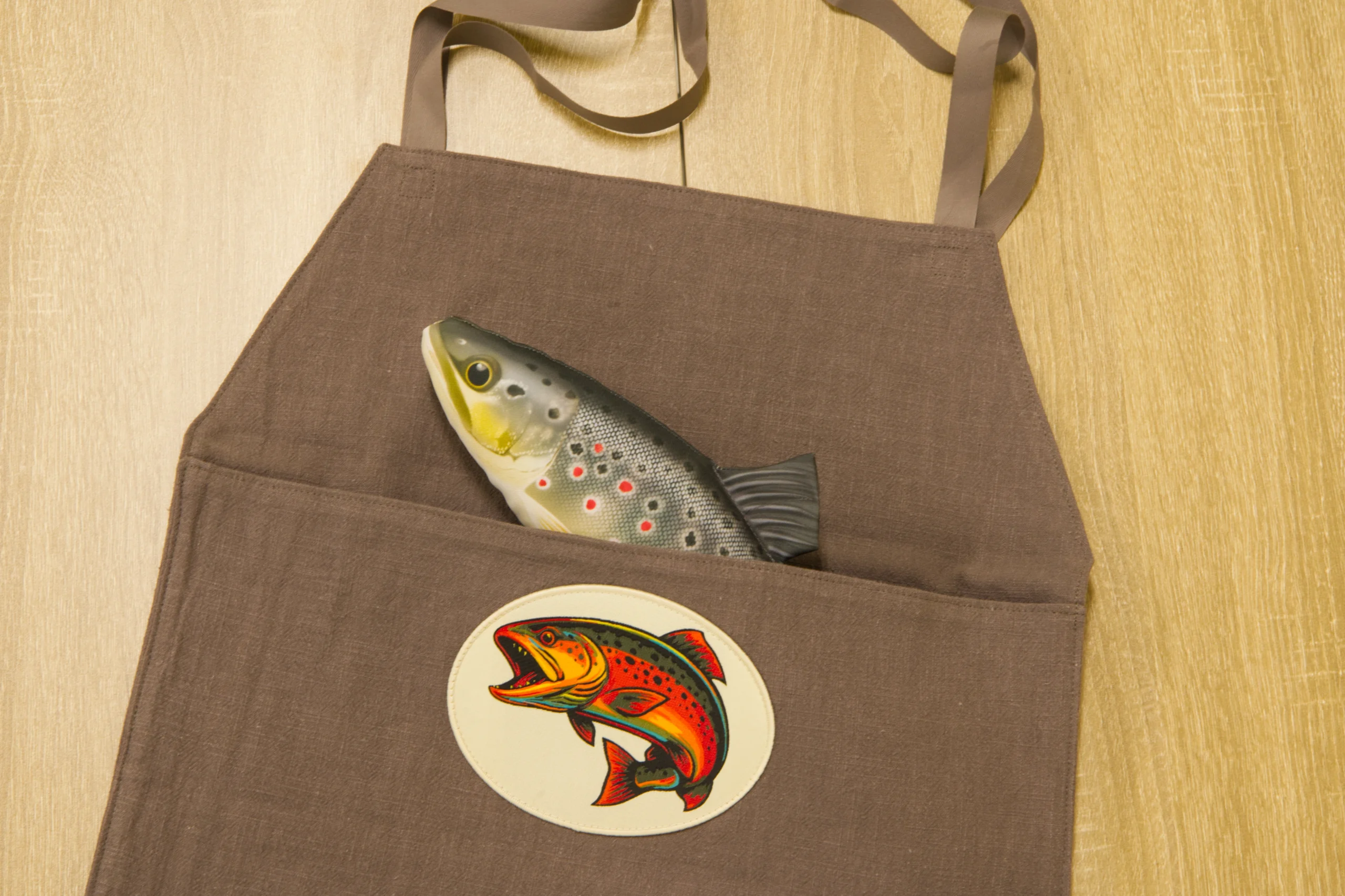 Forelle in Schürzentasche mit Fisch-Aufnäher. Sicherer Fischtransport.