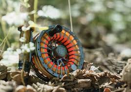 Fliegenfischen Rolle mit orangefarbener Schnur, liegend im Laub. Top Ratgeber für Einsteiger.