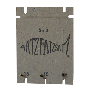 Eine strukturierte quadratische Karte mit „BATZFATZSATZ“ in verzerrten schwarzen Buchstaben, der Zahl „546“ darüber und „18“ und „8“ darunter, mit kleinen Löchern und Fäden – Teil der Serie RatzFatzSatz 546 (Gold, Braun & Silber).