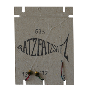 Eine hellbraune Karte mit der Aufschrift „RatzFatzSatz 635 (Rot & Grün)“ zeigt eine schwarze Fischgrafik, Zahlen und zwei Angelfliegen – eine rote (rot) und eine grüne (grün) –, die an der Unterseite an einer Angelschnur befestigt sind.