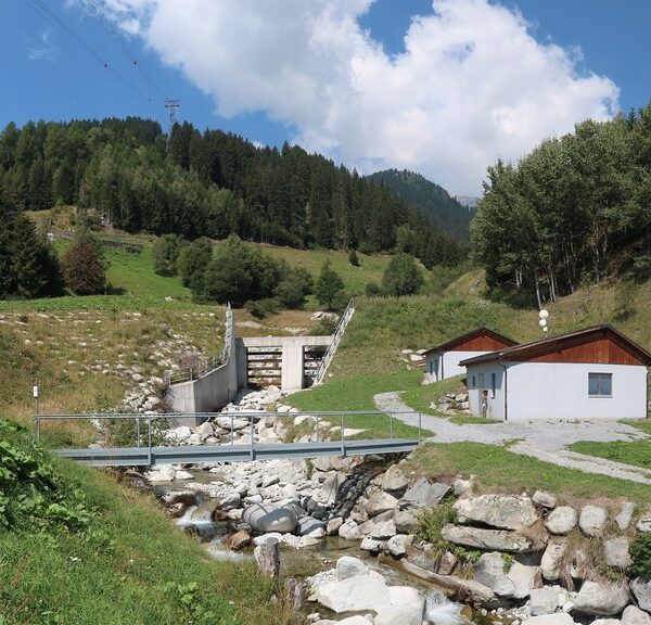 Acletta: Wasserkraftwerk am Fluss in grüner Landschaft.