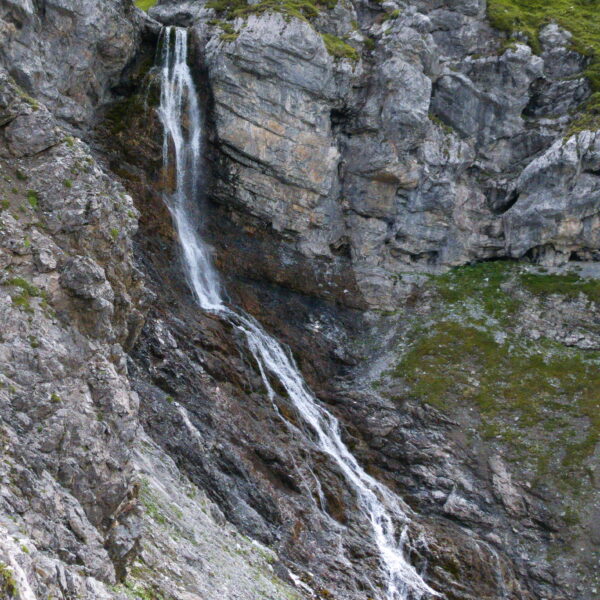 Alteinbach Wasserfall stürzt über eine felsige Bergwand herab. Grün bewachsene Felsen.
