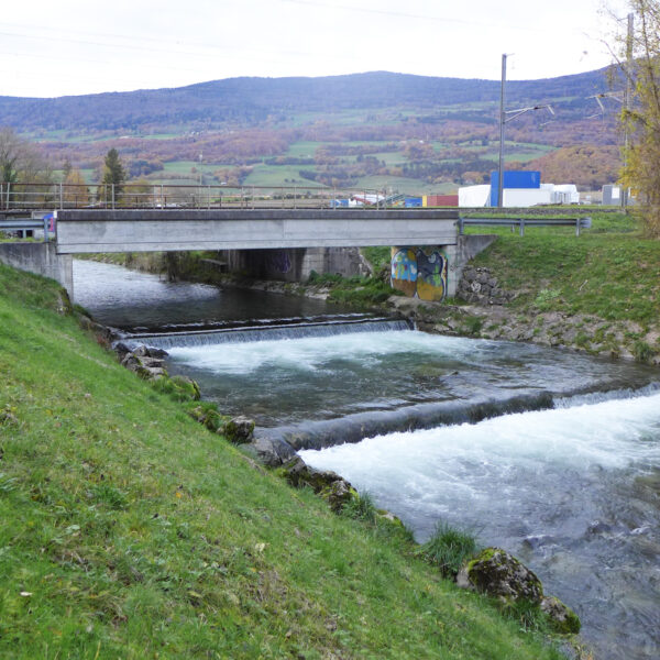 Brücke über den Arnon-Fluss mit Wasserfällen und Hügeln im Hintergrund.