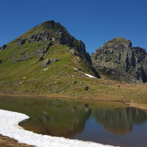 Berglimattsee mit Spiegelung der Berge und Schneefläche im Vordergrund.