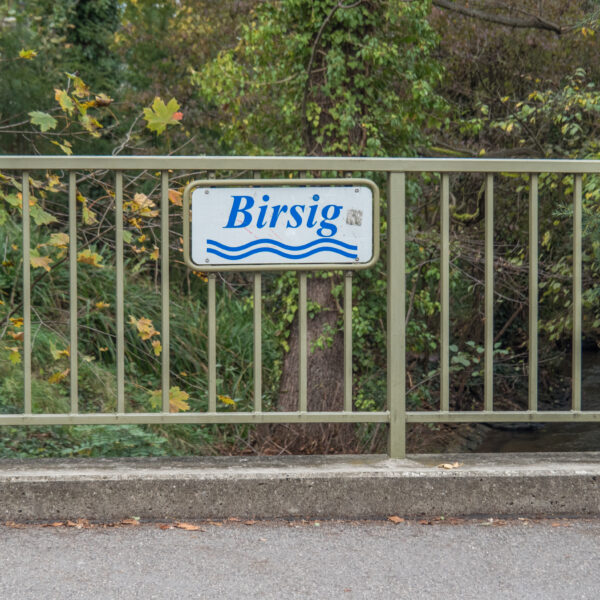 Birsig-Schild auf einer Brücke über den Fluss. Der Name des Flusses ist auf dem Schild abgebildet.