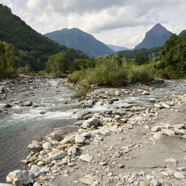 Brenno Fluss in malerischer Berglandschaft mit Felsen und grünen Hängen.