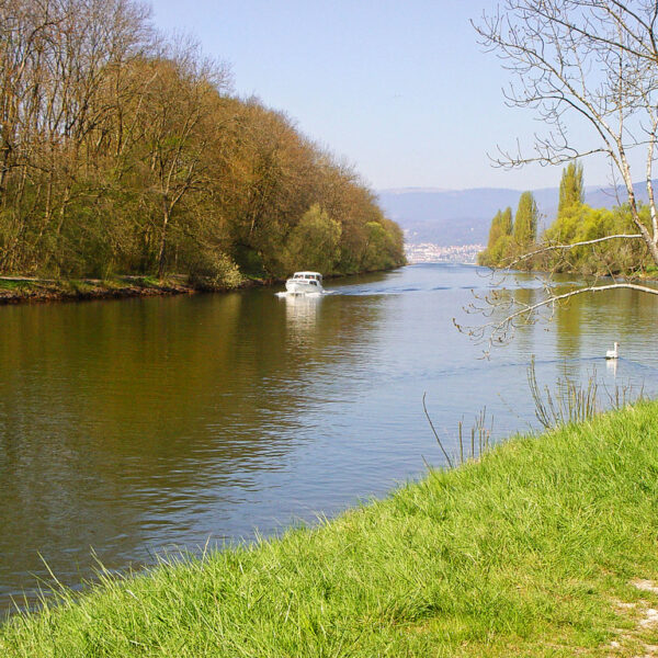 Boot auf dem Canal de la Broye, umgeben von grüner Natur und Bäumen.