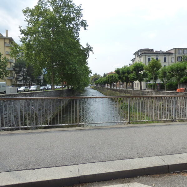 Cassarate Fluss in Lugano, Schweiz mit Brücke und Gebäuden.