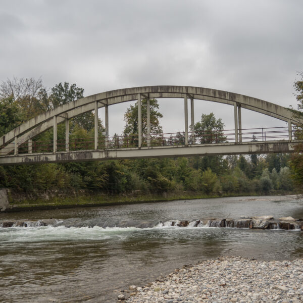 Emme-Brücke über den Fluss, ruhige Landschaft mit Bäumen und Steinen.