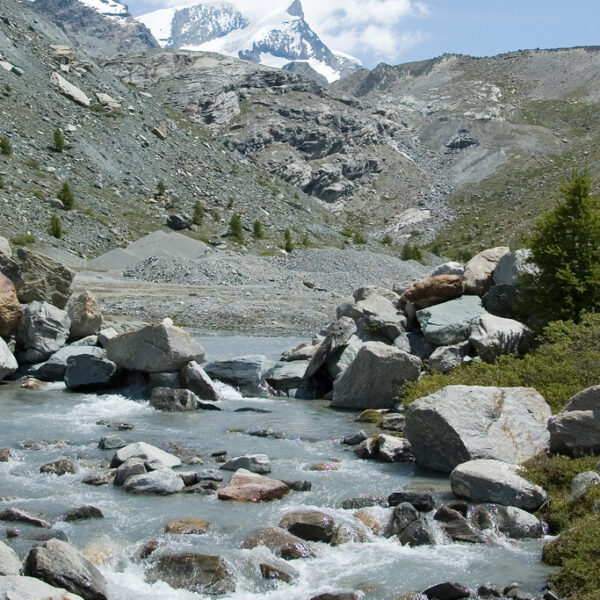 Findelbach-Fluss mit schneebedeckten Bergen im Hintergrund, Zermatt, Schweiz.