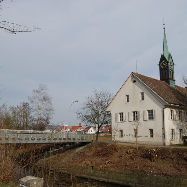 Kirche mit Turm in Glatt (Zürich) neben einer Brücke.