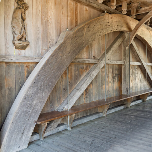 Holzbrücke Grosse Aa mit Sitzbank und geschnitzter Figur an der Wand.