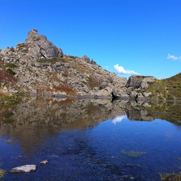 Hauenseeli: Bergsee mit Felsen und klarer Spiegelung des Himmels.