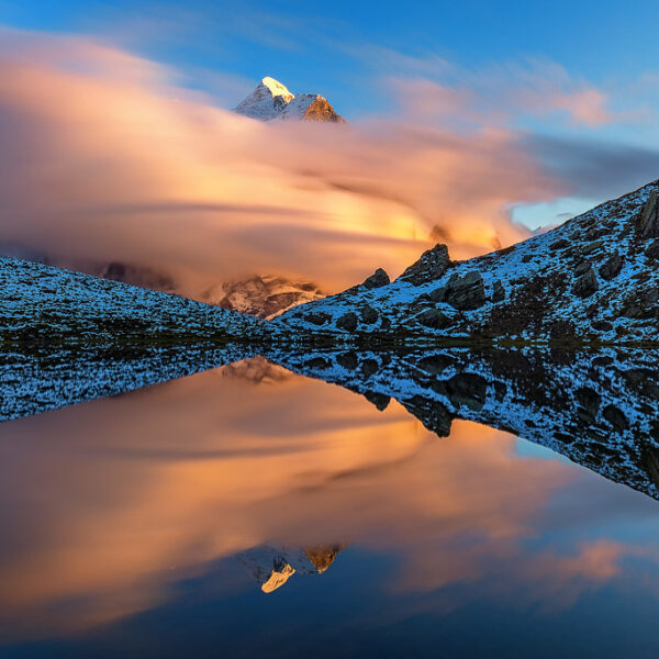 Hornseeli Spiegelung: Bergspitze ragt aus Wolken über einem ruhigen See.