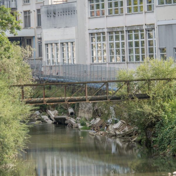 Jaunbach-Fluss mit einer alten Brücke und Gebäuden im Hintergrund.