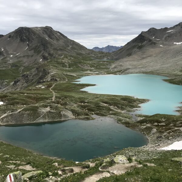 Türkisblaue Jöriseen in den Schweizer Alpen unter bewölktem Himmel.